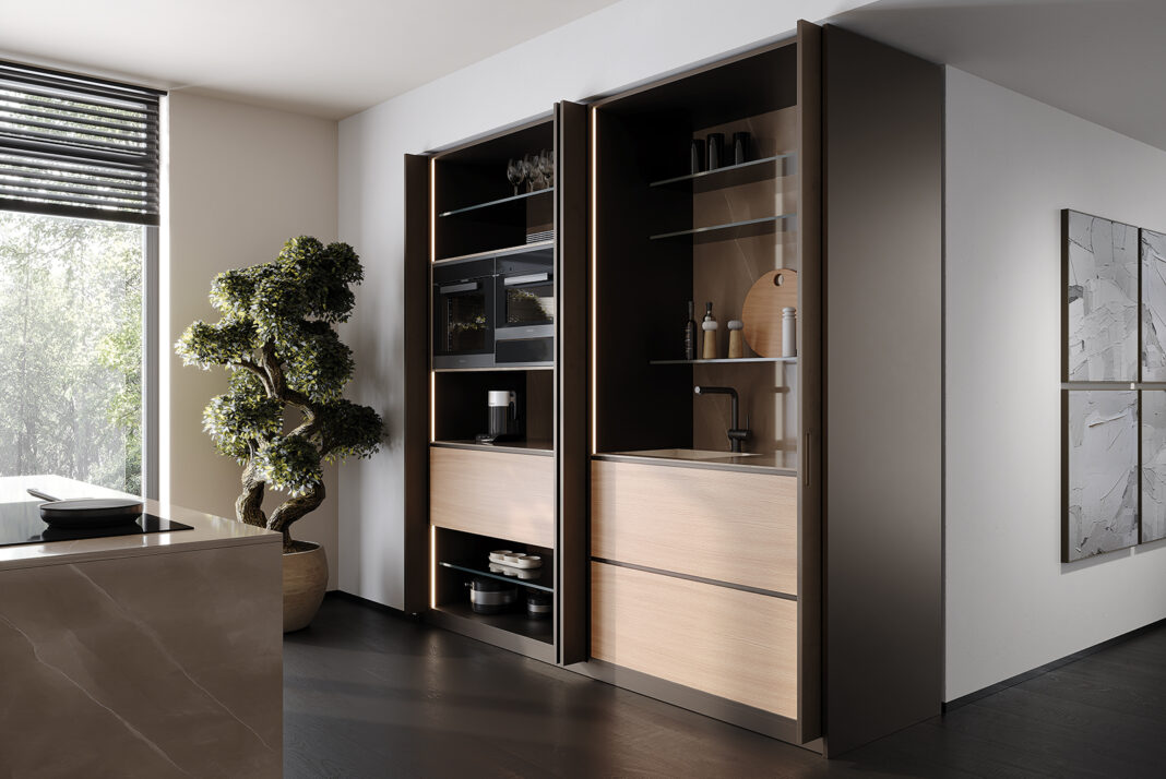Σύστημα POCKET DOOR PB15 της Cinetto σε λειτουργία, με ξύλινες πόρτες που αποκαλύπτουν σύγχρονο χώρο κουζίνας με ηλεκτρικές συσκευές και πάγκο εργασίας.