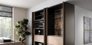 Σύστημα POCKET DOOR PB15 της Cinetto σε λειτουργία, με ξύλινες πόρτες που αποκαλύπτουν σύγχρονο χώρο κουζίνας με ηλεκτρικές συσκευές και πάγκο εργασίας.